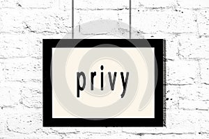 Black frame hanging on white brick wall with inscription privy