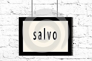Black frame hanging on white brick wall with inscription salvo