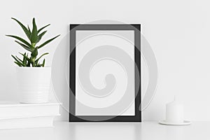 Black frame mockup with workspace accessories and a aloe vera on a white table.Portrait orientation