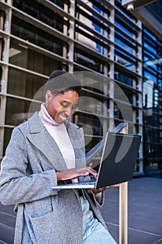 Black freelancer using laptop on street