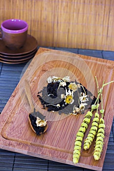 Black friable tea with sage and camomile on wooden spoon on tray