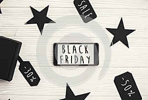 Black Friday big sale text on phone screen. Special discount christmas offer. Phone with advertising message at gift boxes and pr