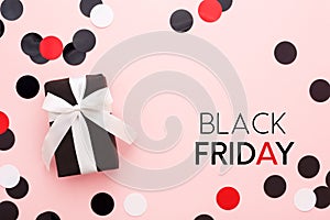 Black friday card with gift box and confetti on pink background.