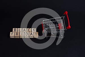 Black Friday the concept of sales in the store, cubes with the words black Friday and the supermarket cart on black background