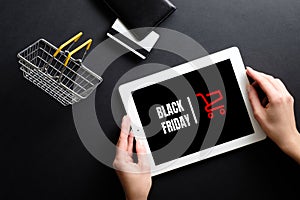 Black Friday concept. Tablet with sign `Black friday` on screen, shopping card, credit card over black background