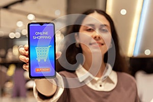 Black friday. Defocused portrait of happy young Caucasian woman shows smartphone with purchases in online store on