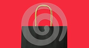 Black Friday. Paper black shopping bag on the red background. Mock up. Autumn sale. Place for text