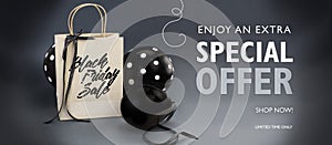 Black Friday sale banner containing recycled paper bag decorated with black satin ribbon, and black balloons. photo