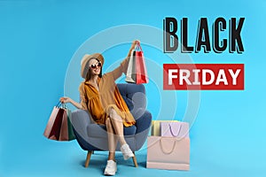 Black Friday Sale. Beautiful young woman with shopping bags sitting in armchair on light blue background