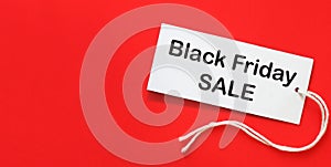 Black Friday sale. Clothing tag with inscription Black Friday on red background. Advertising of discounts. Copy space for text