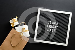 Black Friday sale concept. Letter board with sign `Black Friday sale`, shopping bag and gift boxes over black background. Flat lay