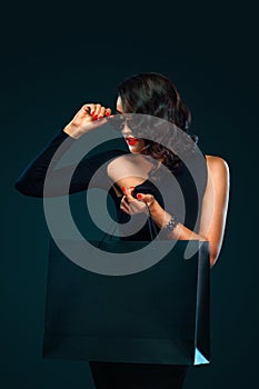 Black Friday sale concept for shop. Beautiful girl in sunglasses holding big bag isolated on dark background at shopping