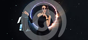 Black Friday sale concept for shop. Girl in sunglasses holding big bag isolated on dark background at shopping. Neon