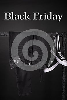 Black friday. Sale sign. and white sneakers pant, jeans hanging on clothes rack background. Close up.