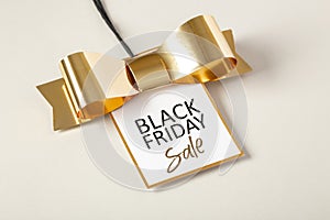 Black friday sale tag with gold border and bow on beige background