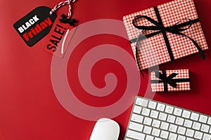 Black Friday Sale text on a red and black tag with Alarm Clock, keyboard computer and gift box on red background.