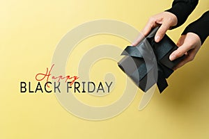 Black Friday sale, woman hand give the gift box on yellow background