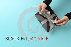 Black friday sale, woman hand give the gift box on yellow background