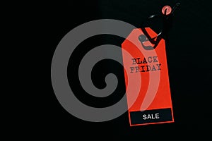 Black friday shopping sale concept. Text on red tag on black wooden background. Copy space