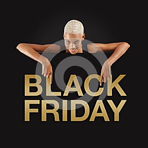 Black Friday shopping. Smiling black woman pointing at a Black Friday golden text on advertising banner commercial sign. Store and