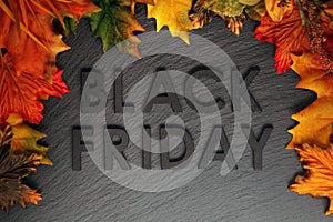 Black Friday text with autumn leaves on black slate