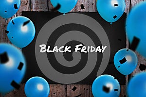 Black Friday text on black paper surrounded with blue ballons and black confetty