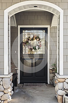 Black front door of a home seen through an arch