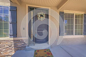 Black front door with lockbox, wreath, and side panel