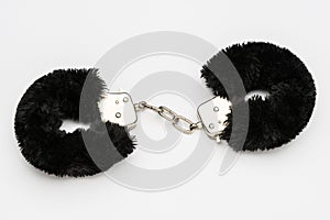 Black furry handcuffs on white background