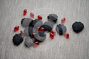 Black gac seeds and oil pills on neutral background.