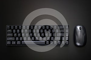 Black gaming compact ergonomic computer keyboard and computer mouse on a dark background. Wireless technology and gadgets. Copy