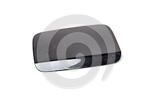 Black gas tank hatch on a white isolated background in a photo studio. Spare part car body cover when repairing the fuel system in