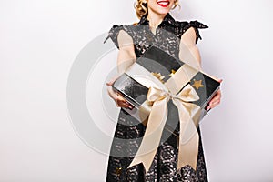Black gift box in her hands on white background, red lips, black dress, surprise emotion.