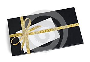 Black gift box (present) with golden ribbon bow and a blank card with copy space