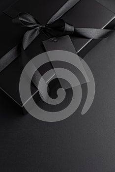 Black Gift Box with Satin Ribbon and Blank Tag on Dark Background