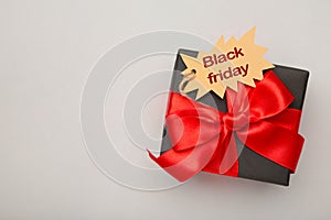 Black gift with sale tag on grey background. Black Friday sales discount composition
