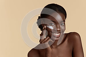 Black girl apply cosmetic cream on face