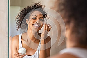 Black girl applying lotion on face