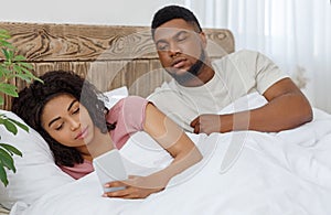 Black girl chatting with lover on cellphone in bed