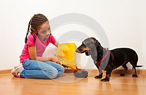 Black girl feed her dog pet with food photo