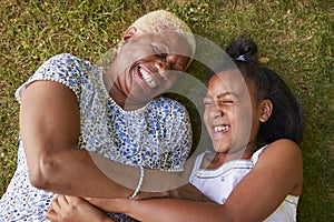 Black girl and grandmother lying on grass, overhead close up