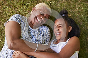 Black girl and grandmother lying on grass, overhead close up photo