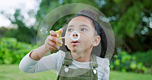 Black girl kid blowing soap bubbles in park, garden and nature, having fun, joy and childhood development, freedom and
