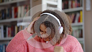 Black girl listening to music and dancing in library