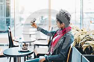 Black girl is making selfie while sitting in office bar