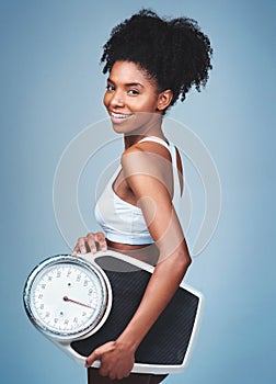 Black girl, portrait and scale in studio to weigh, confident measure and blue background. Female person, fitness and