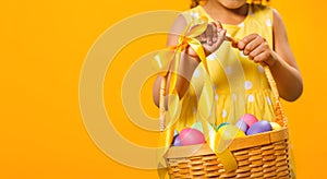 A Black girl with rabbit ears on her head with a basket of colored eggs in her hands