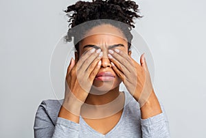 Black girl rubs her eyes, suffering from conjunctivitis