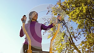 Black girl in sportswear cycling on exercise bike outside