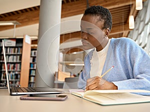 Black girl student using laptop learning online sitting at desk in university.